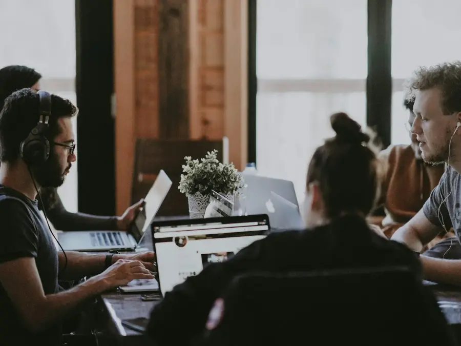 Young adults working on laptops together in a shared workspace