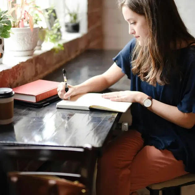 Young woman journaling quietly by a window, representing personal growth through individual therapy and mental wellness